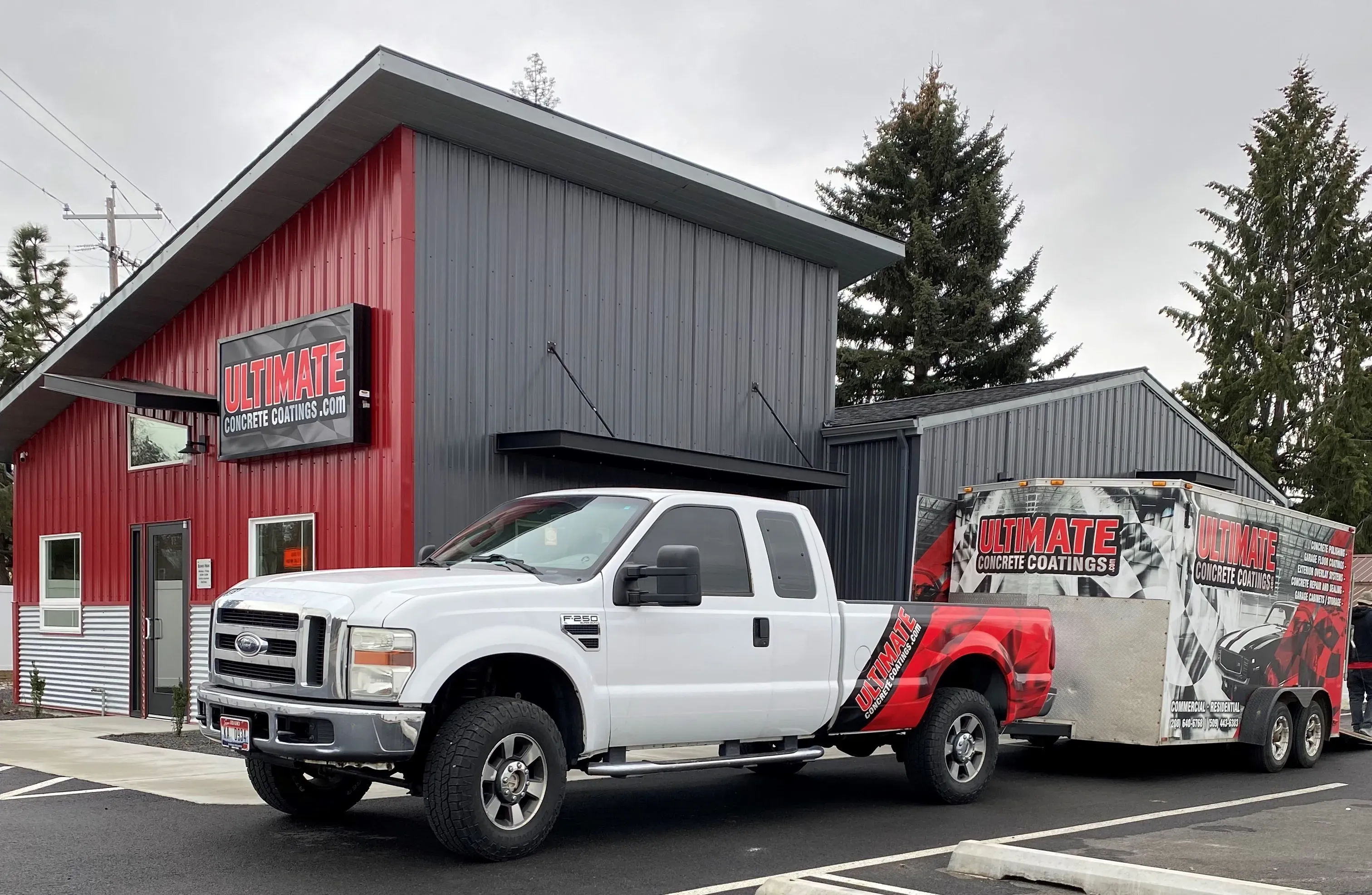 A white Ultimate Concrete Coatings work truck and branded enclosed trailer parked outside the company showroom.